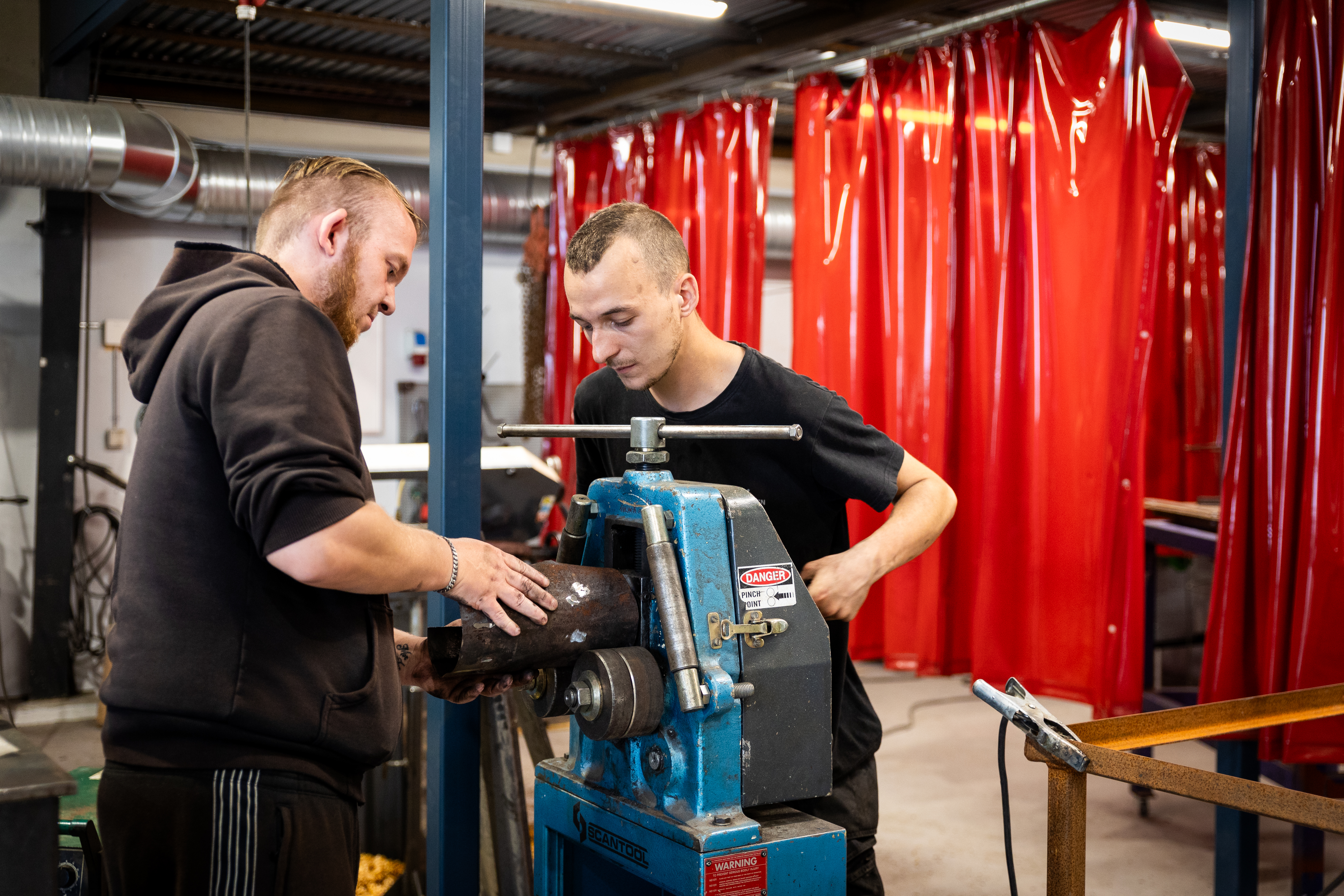 To drenge arbejder med et stykke metal ved en maskine
