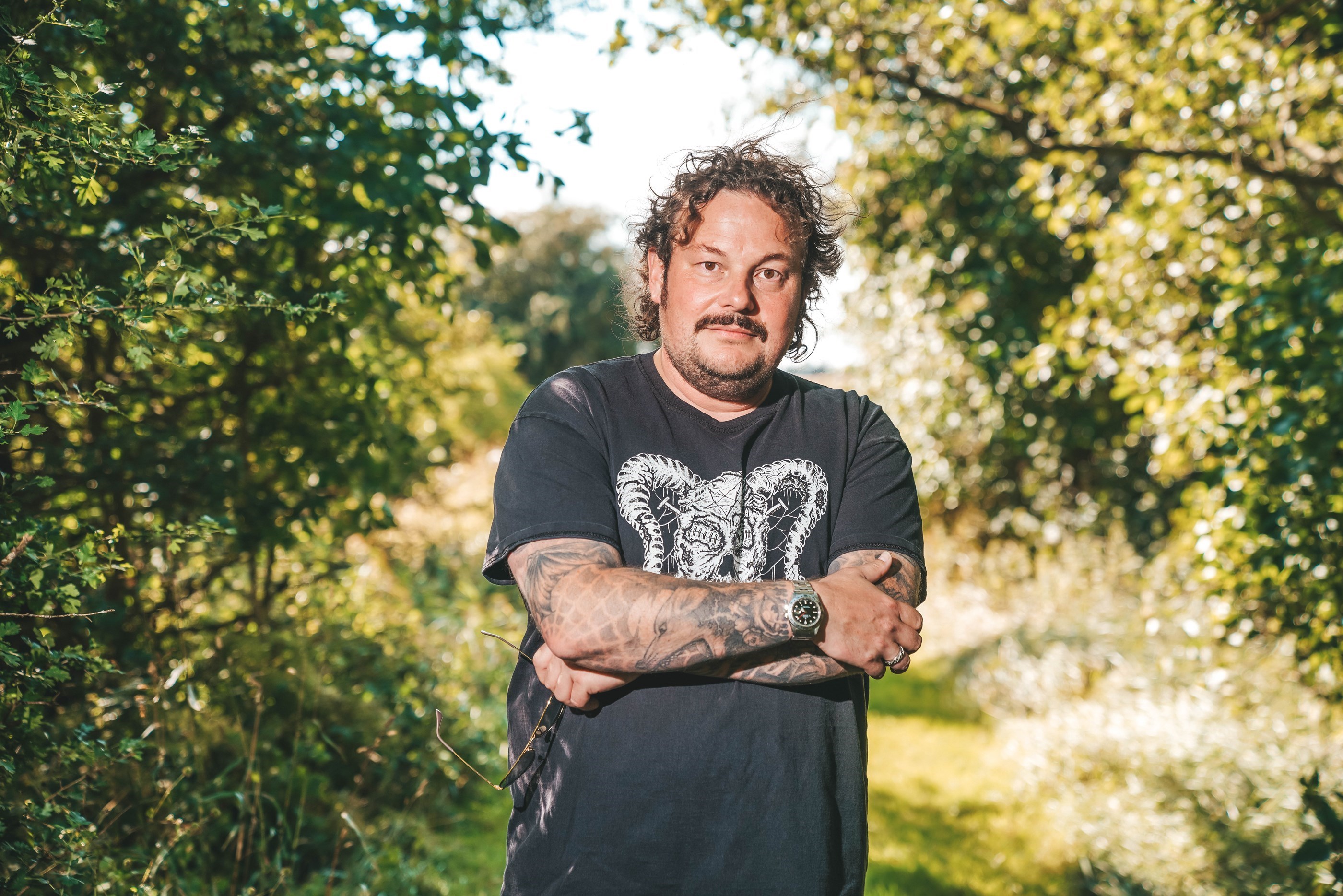 Michael Hvolgaard Andersen står med korslagte arme foran et grønt område