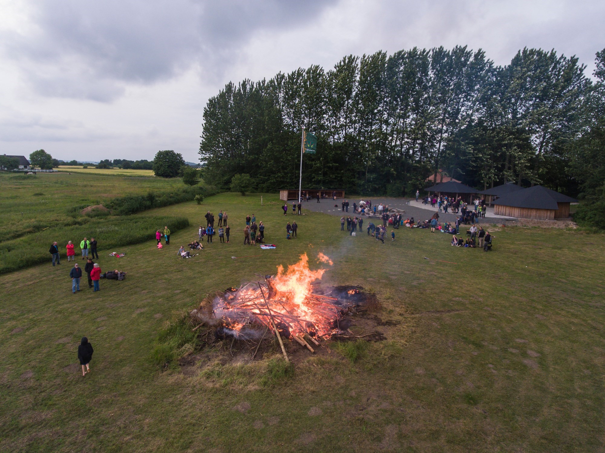 Mennesker står samlet omkring Sankt Hans Bål Ved Friluftszonen i Herlufmagle
