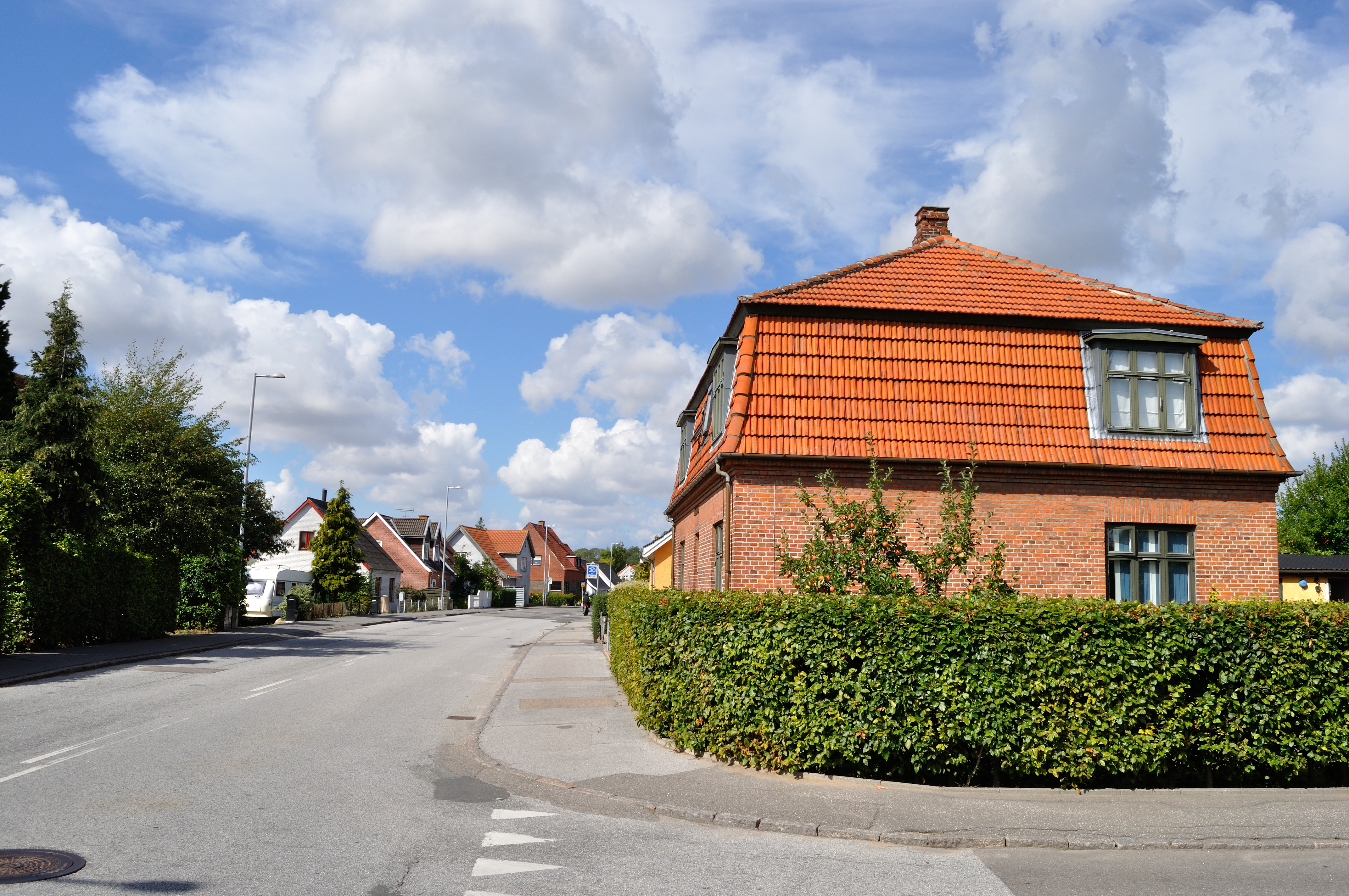 Billed af den privatvej som støder op til en offentligvej med huse ved vejen