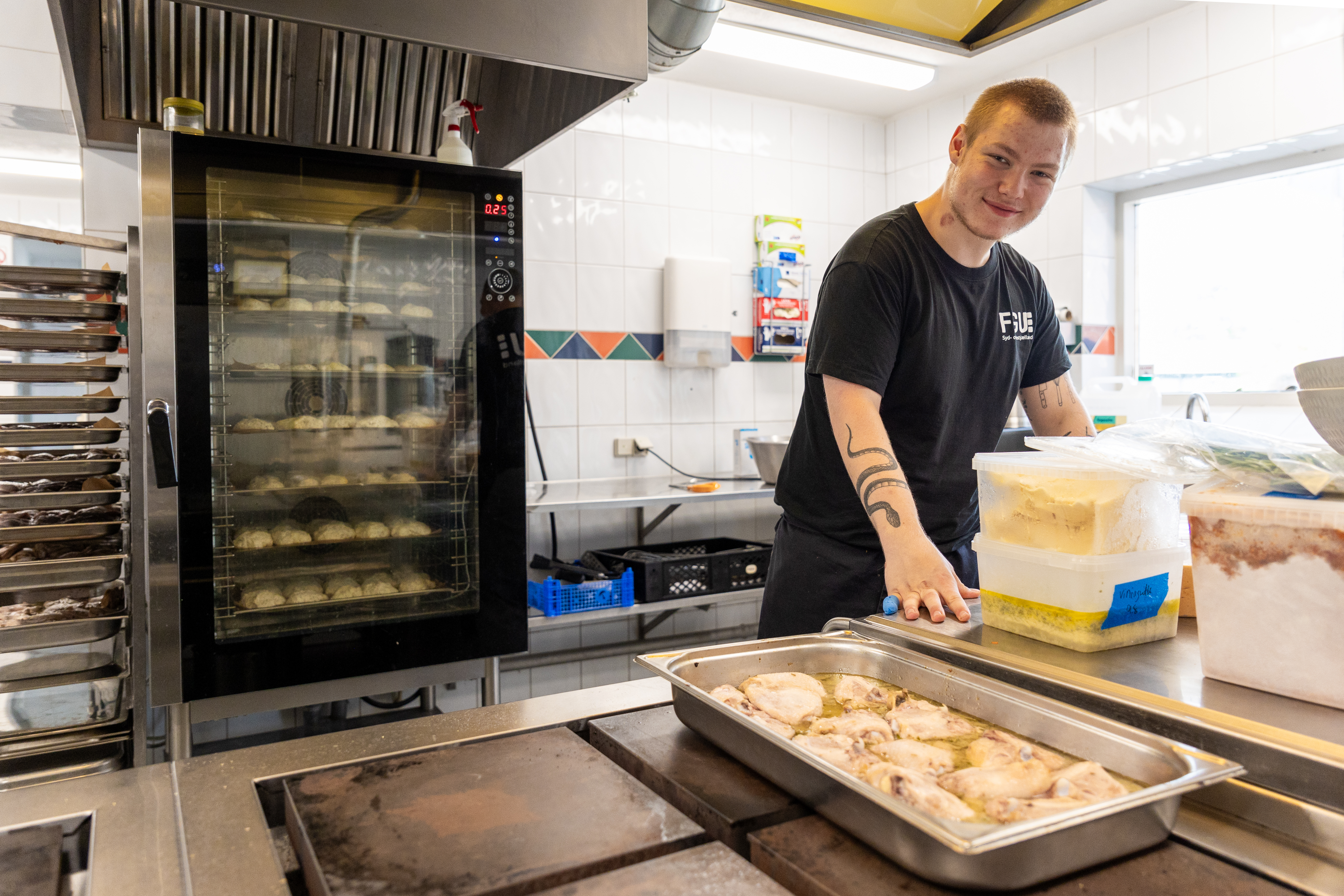 En glad mand venter i et industrikøkken ved siden af en ovn