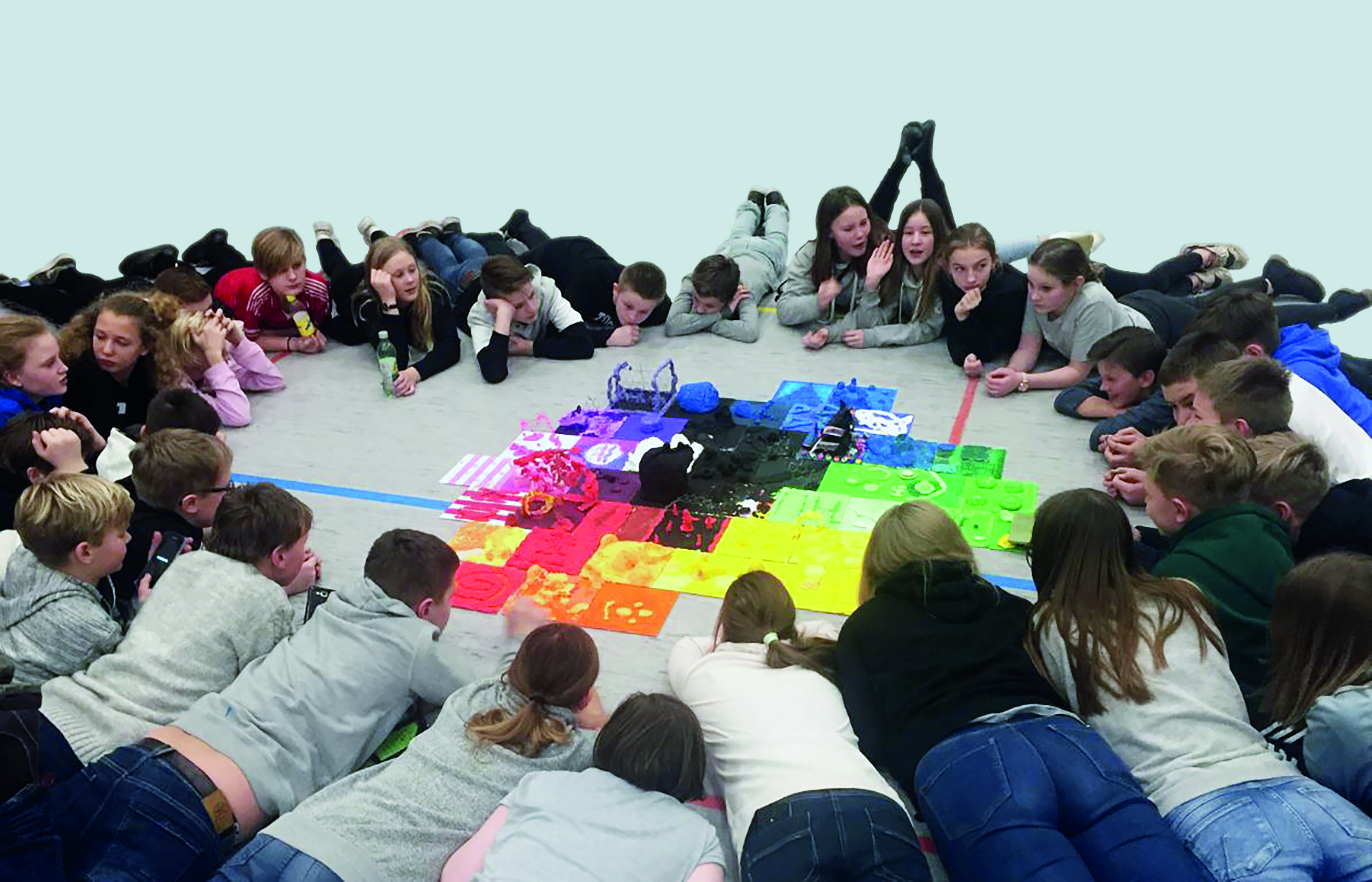 Børn der ligger i en cirkel og kigge på noget de har malet