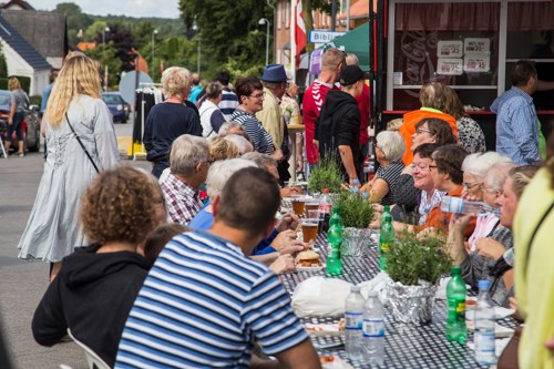 Mennesker sidder udenfor ved et langbord og spiser sammen