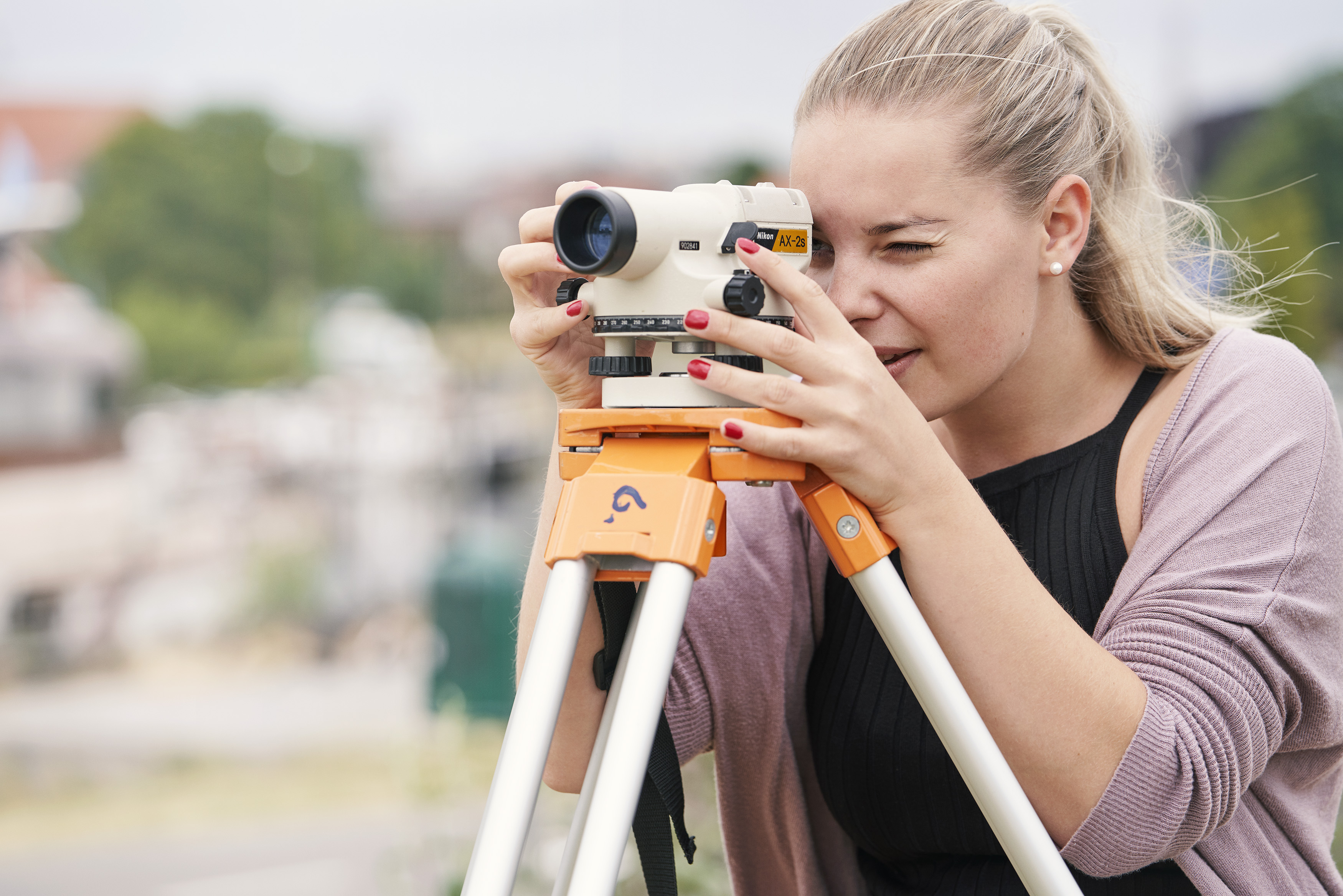 Kvinde står og kigger ind i landmålerudstyr.