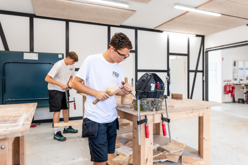 En dreng arbejder med et stykke træ på et bord