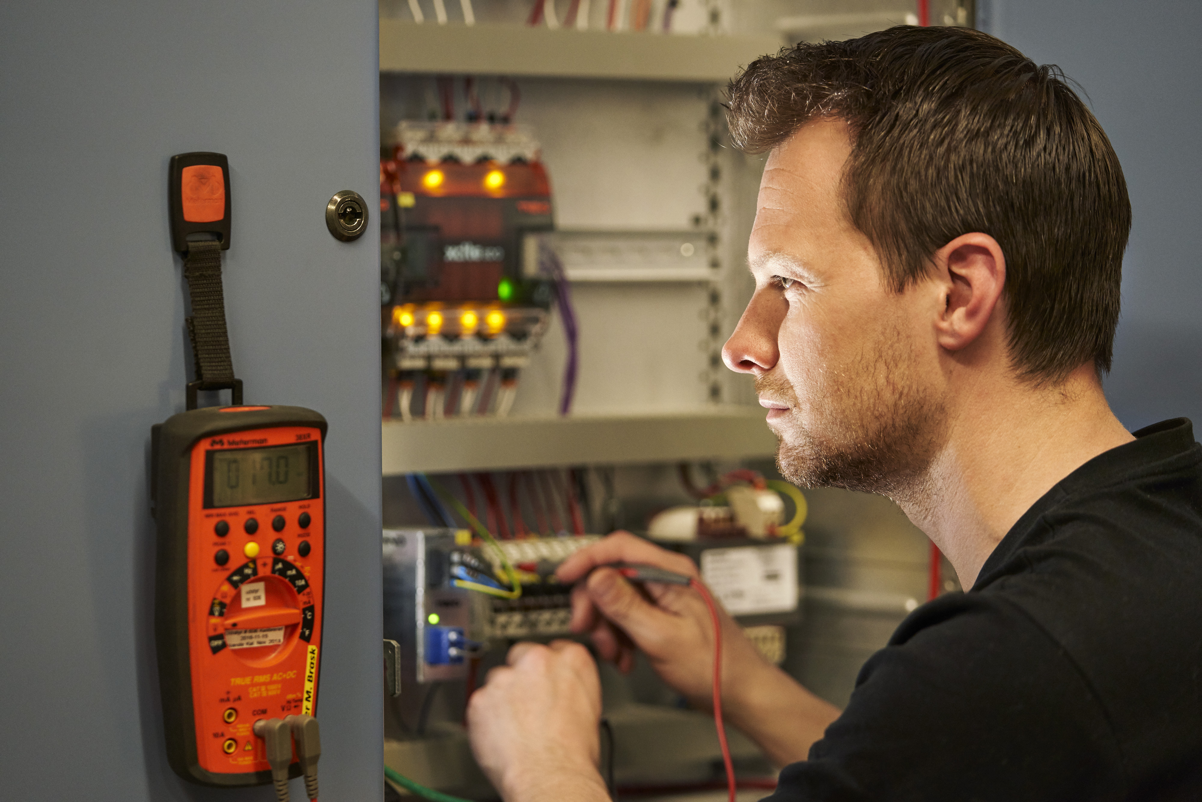 En mand som er el installatør arbejder med et multimeter