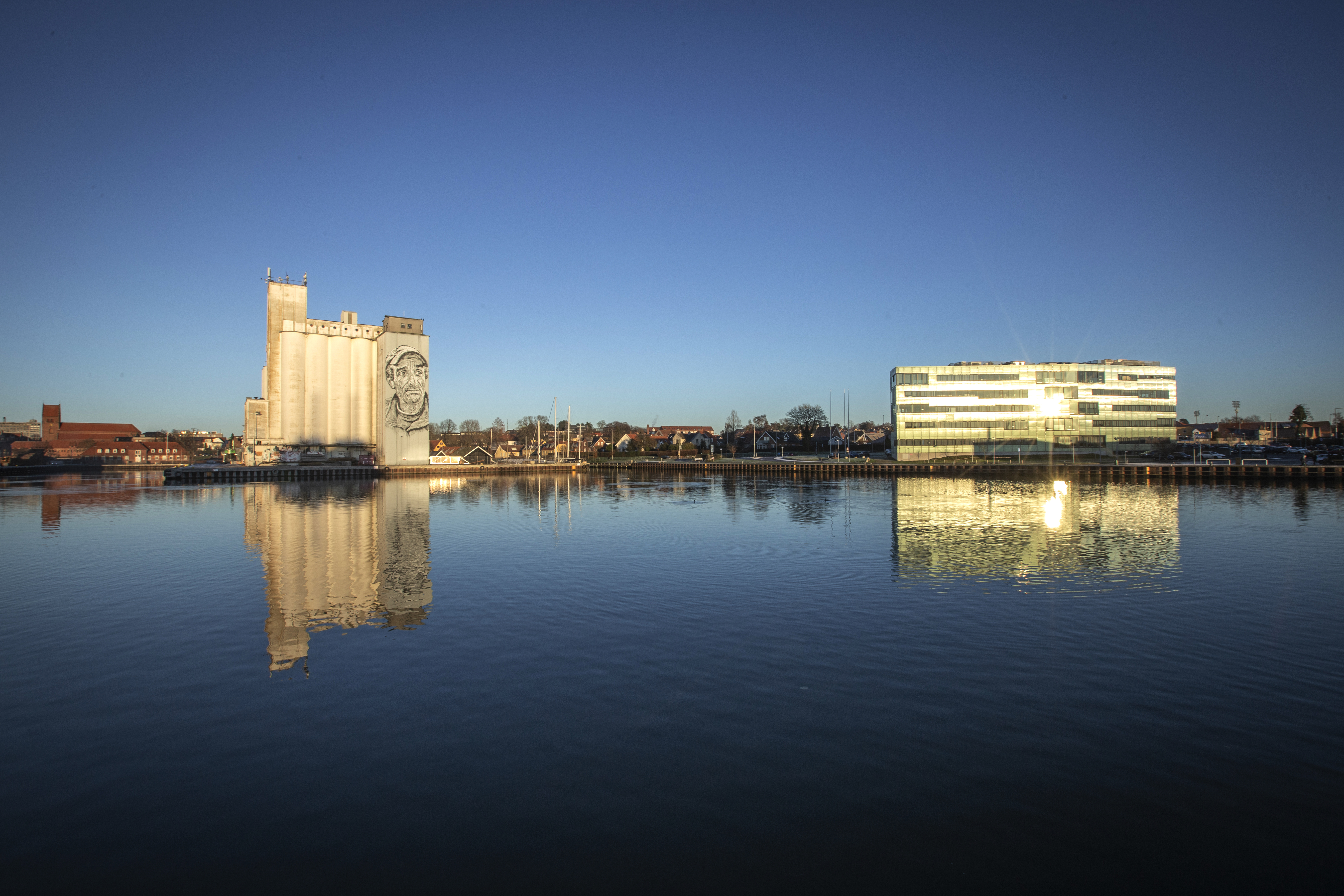 Maxbank-bygningen og siloer spejlet i Næstved havn