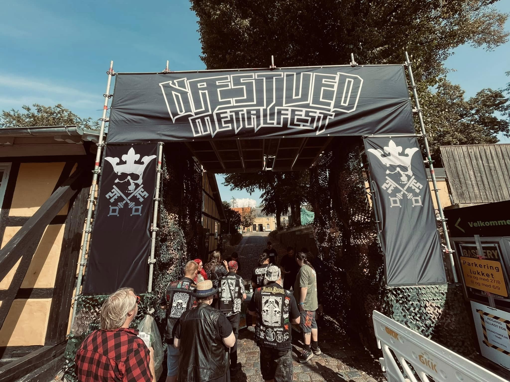Indgangsportal med teksten Næstved Metalfest og sortklædte metalfans på vej ind. 