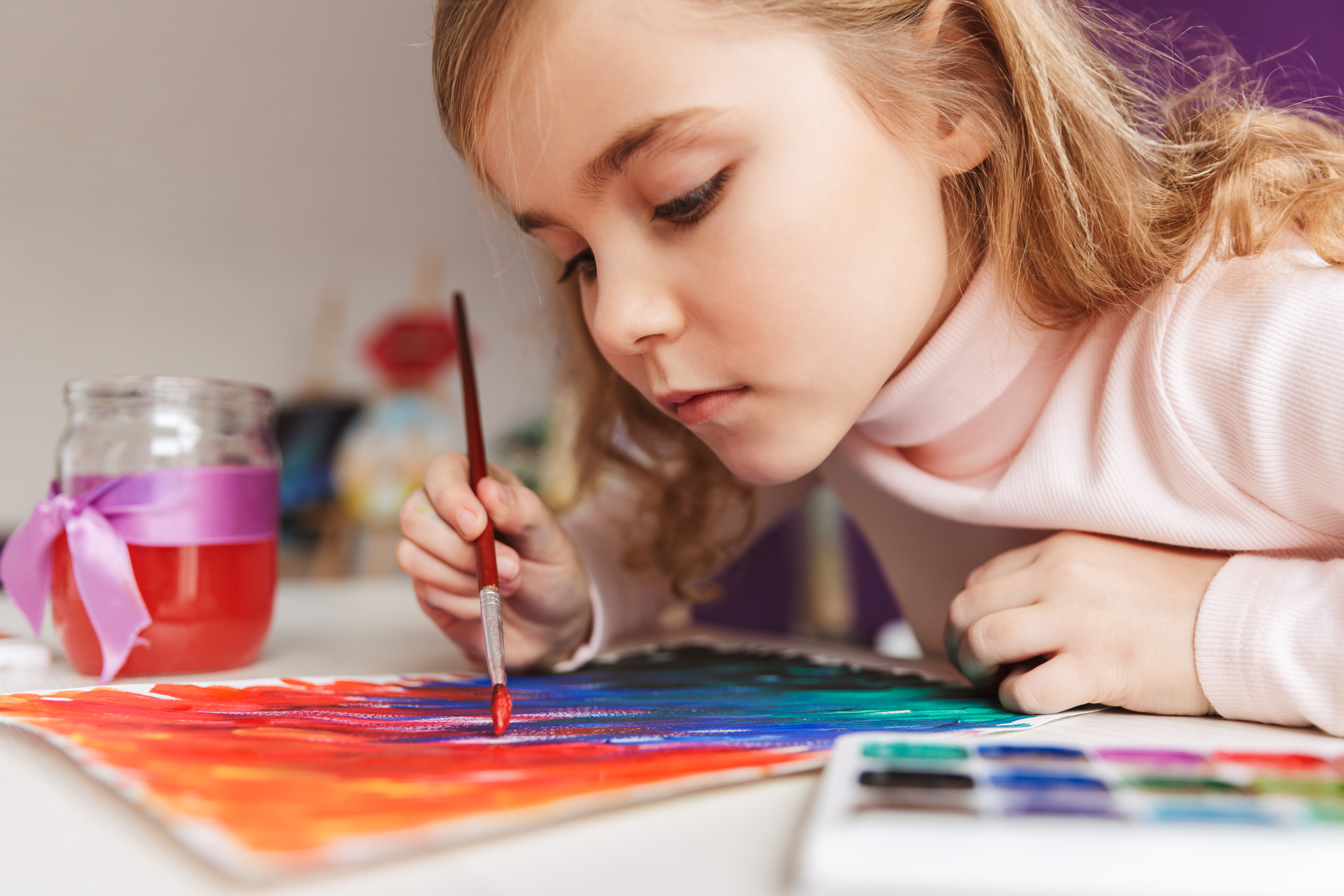 Pige der sidder og maler et abstrakt maleri