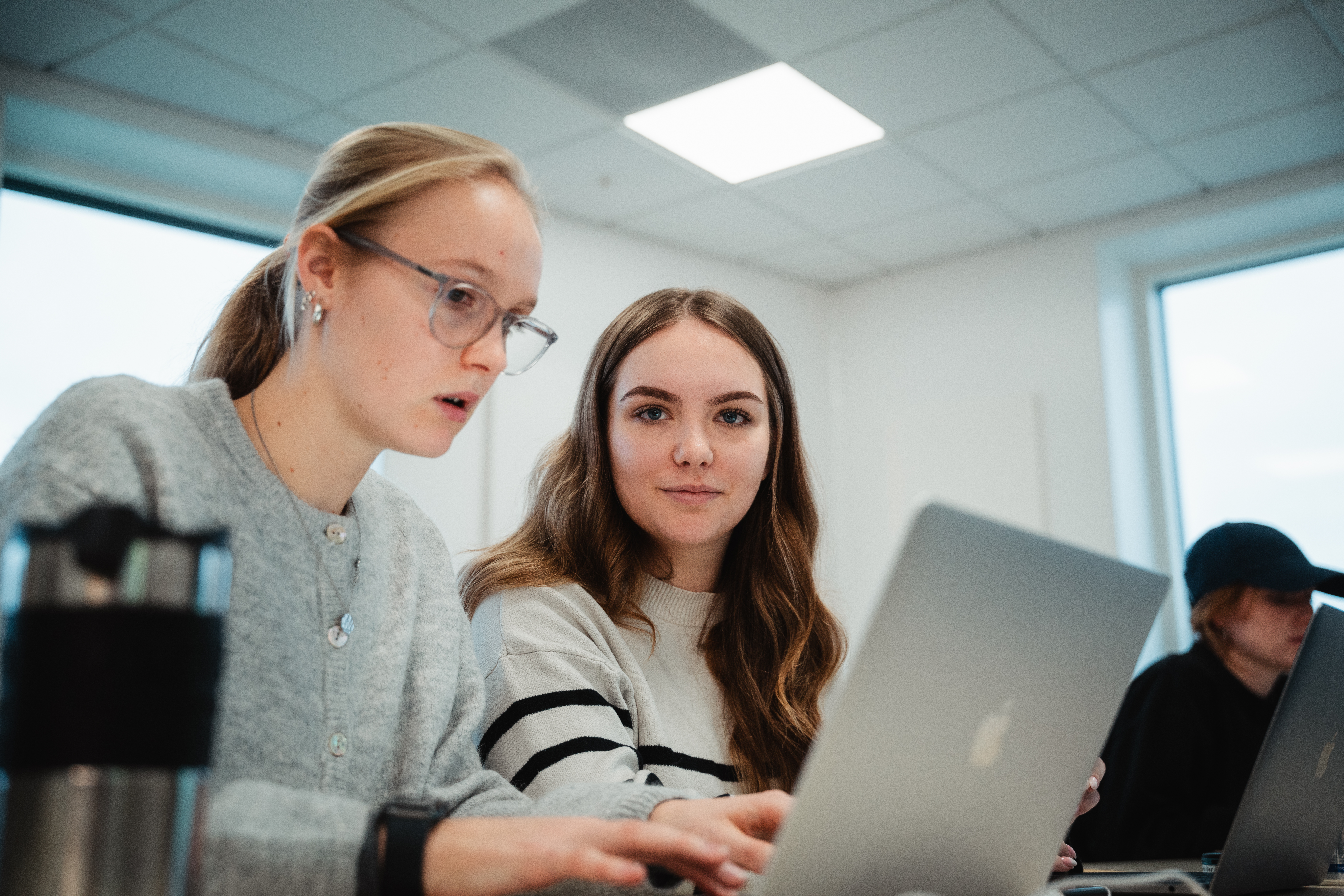 To piger snakker sammen om en opgave med hver deres computer