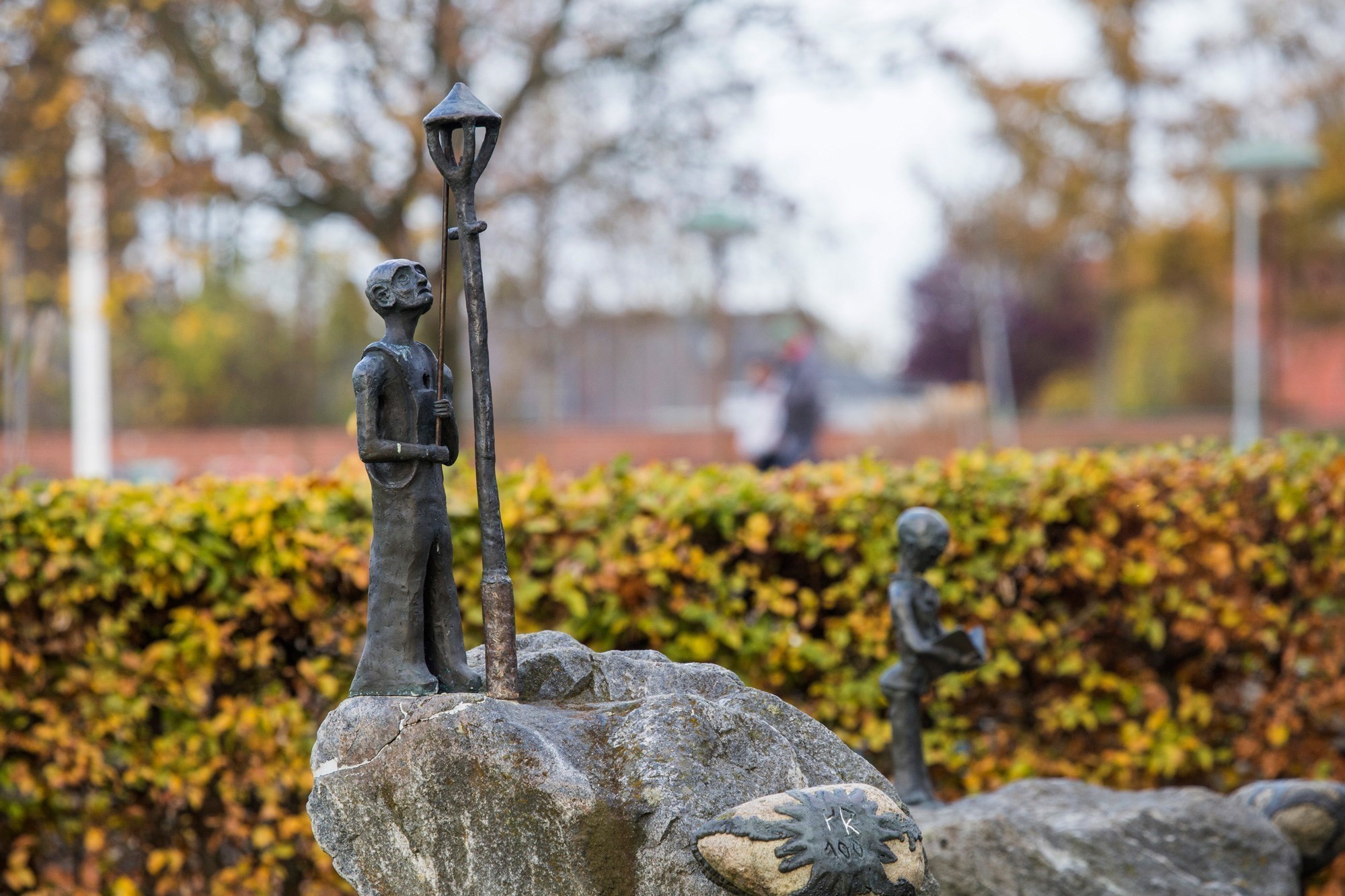 Lille jernfigur af lygtetænder på en sten foran Fuglebjerg bibliotek