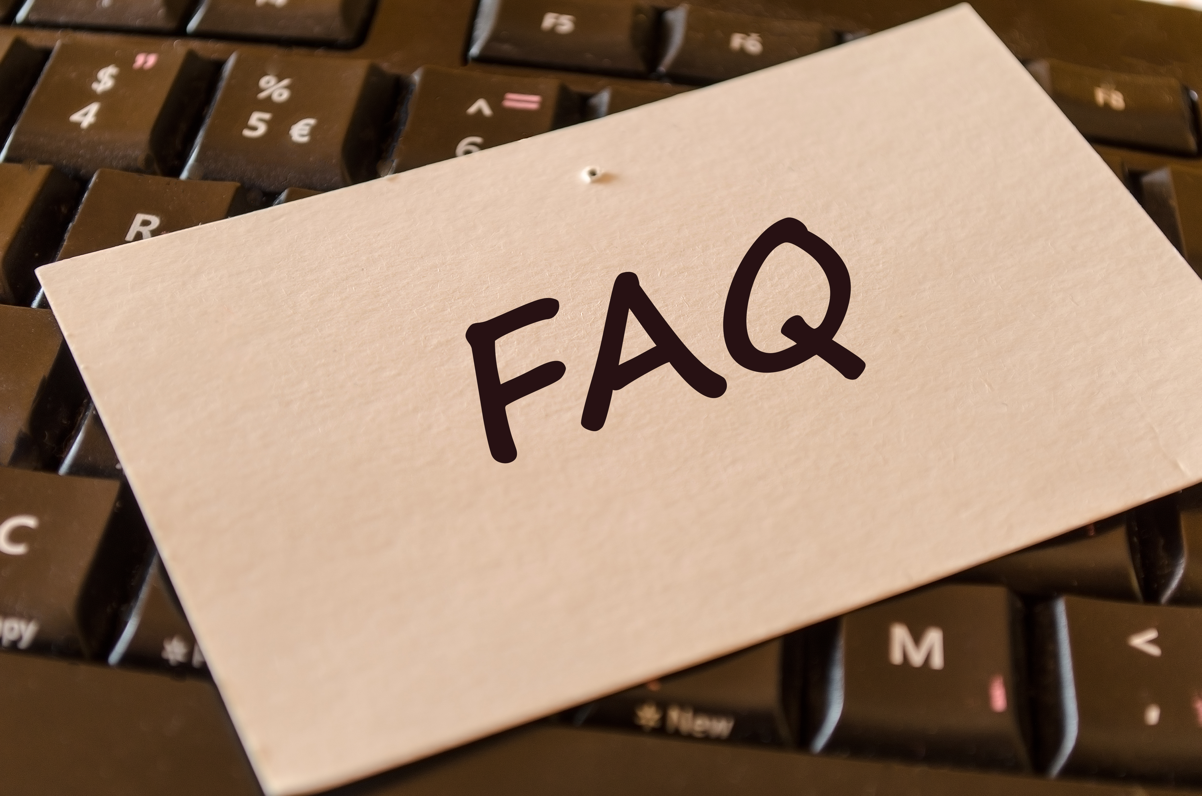 Et skilt med teksten FAQ, som er fastgjort til et tastatur 