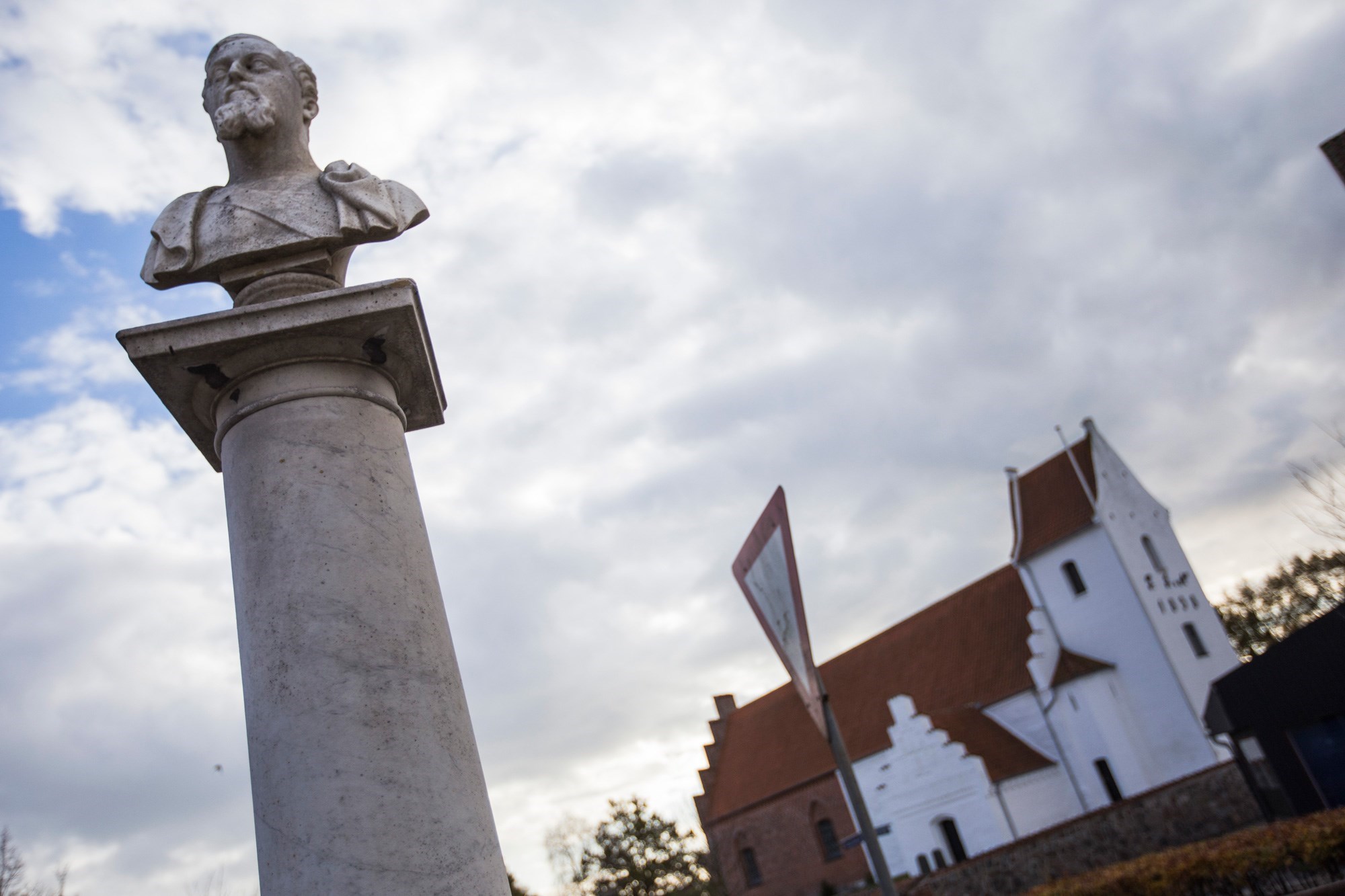 En buste af en mand foran kirken i Fuglebjerg