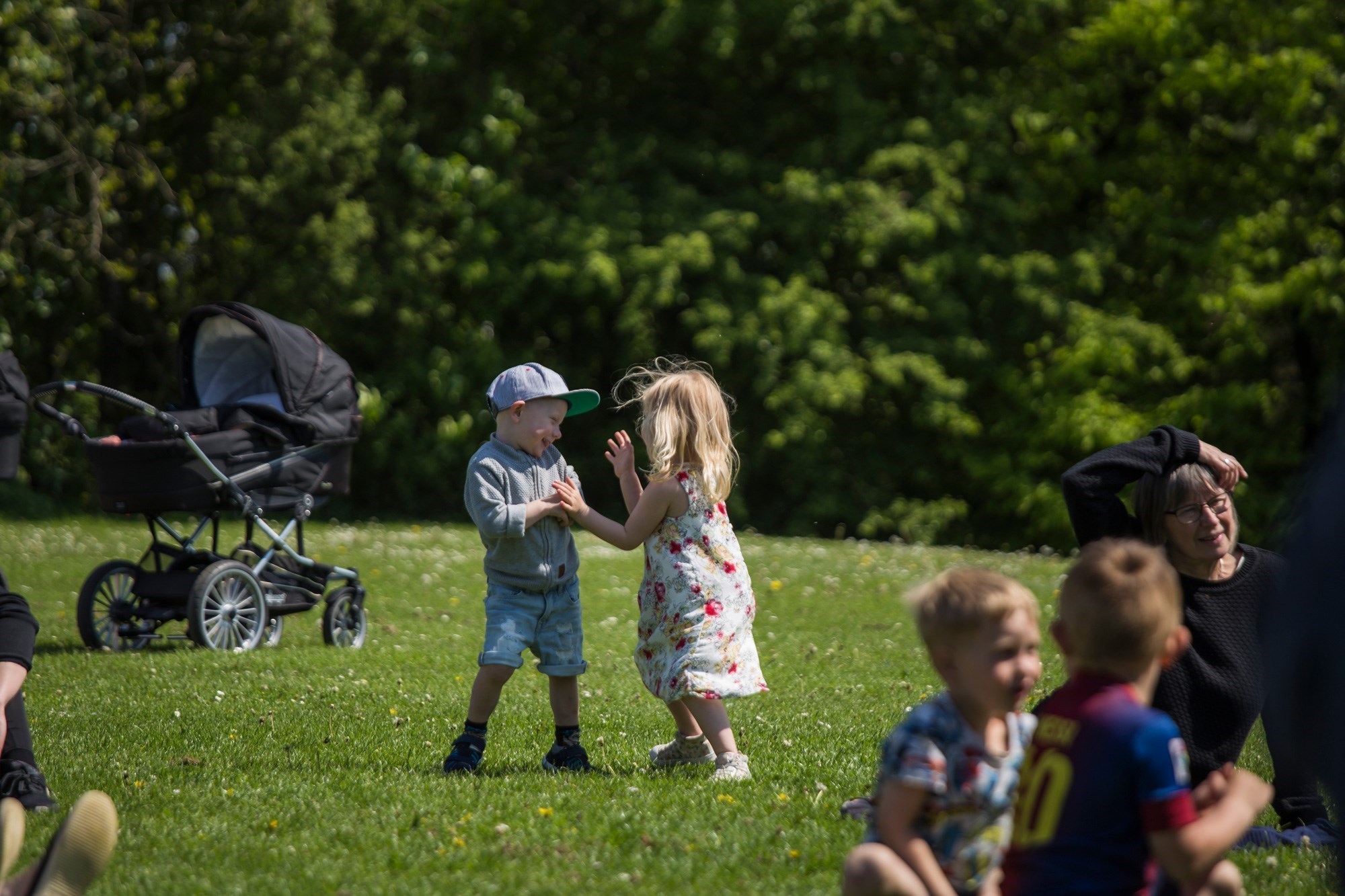 En dreng og en pige leger med hinanden, på græsareal i Mogenstrup