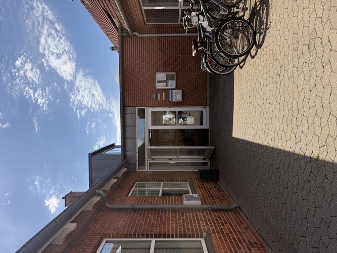 foto af indgangen til aktivitetscenteret Rosengårdens lokaler i 12 N. Den er rundt om bygningen og ikke ud mod gaden.